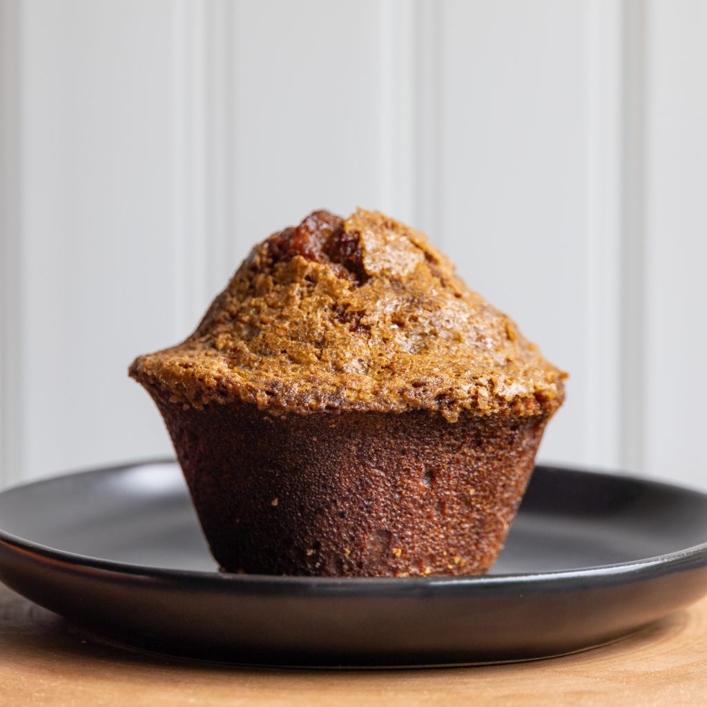 a pumpkin muffin on a black plate in front of a white background